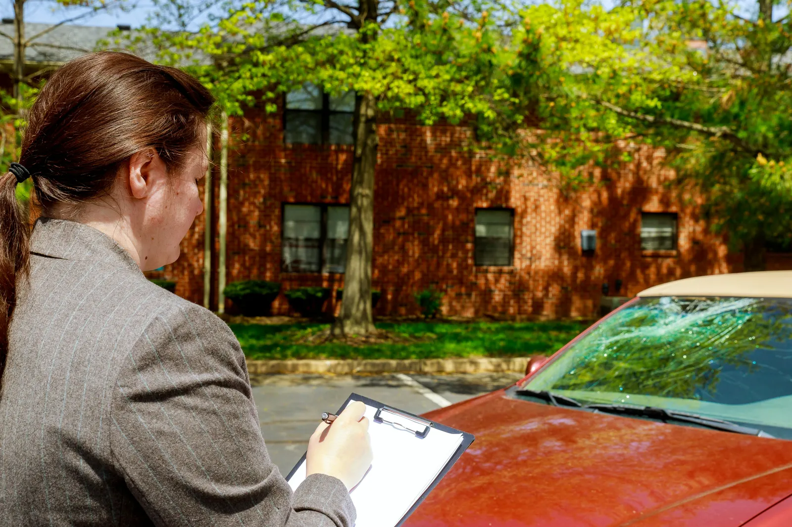 Auto accident report being documented beside a damaged windshield