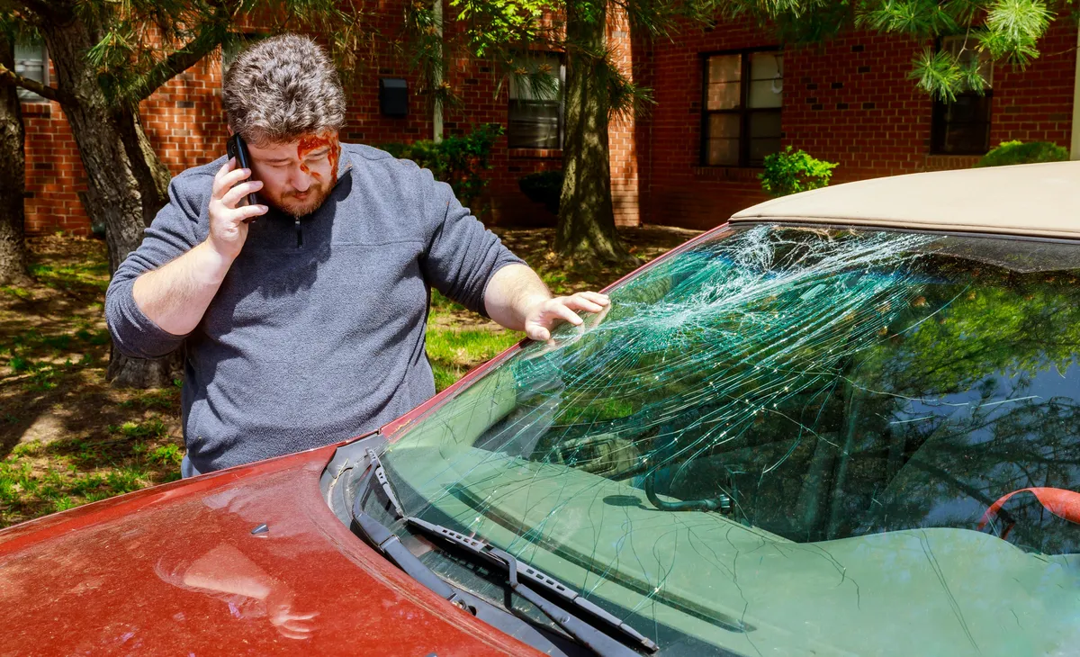 Injured driver calling for help after a windshield accident